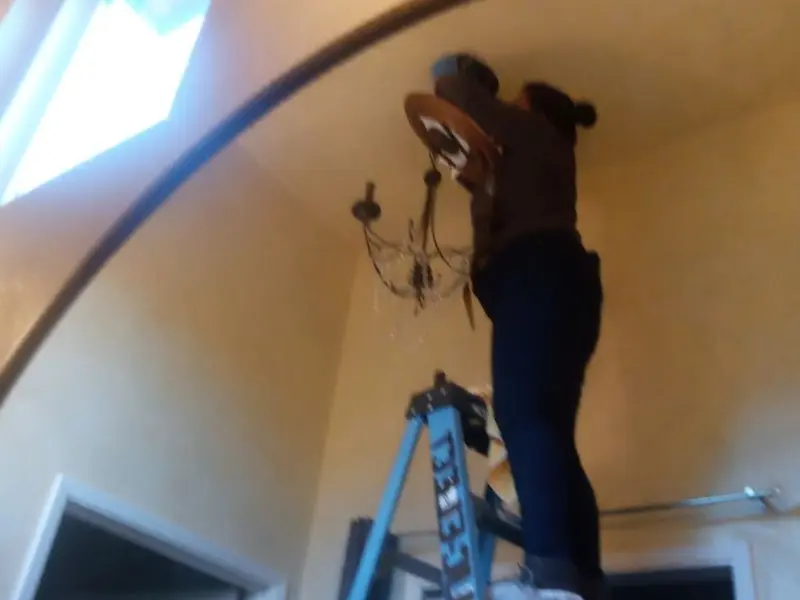 Electrician installing a chandelier in a Hannahs Mill residence